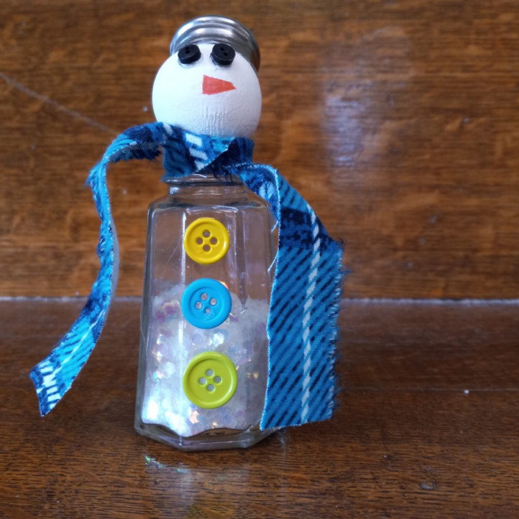 Snowman made from a salt shaker, ribbon, and buttons